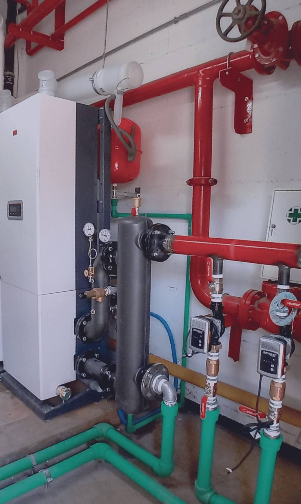 Centrale termica con caldaia, tubazioni rosse e collettori