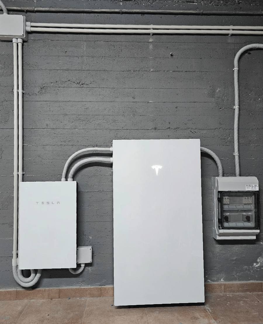 Batteria di accumulo Tesla fissata a un muro, con il quadro elettrico accanto