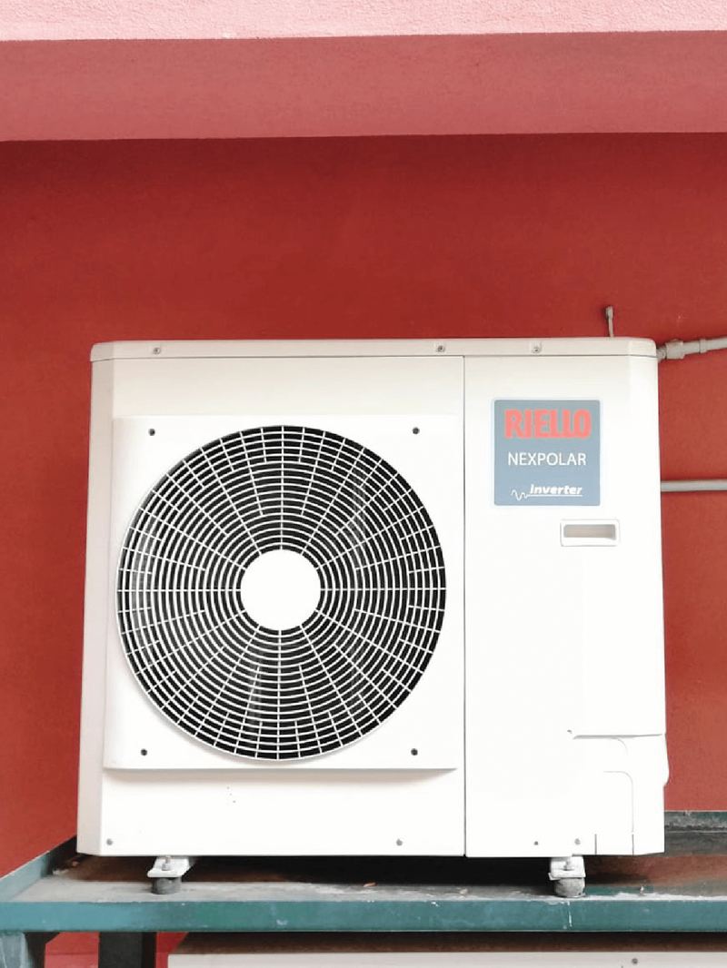 Unità esterna di una pompa di calore su un muro rosso